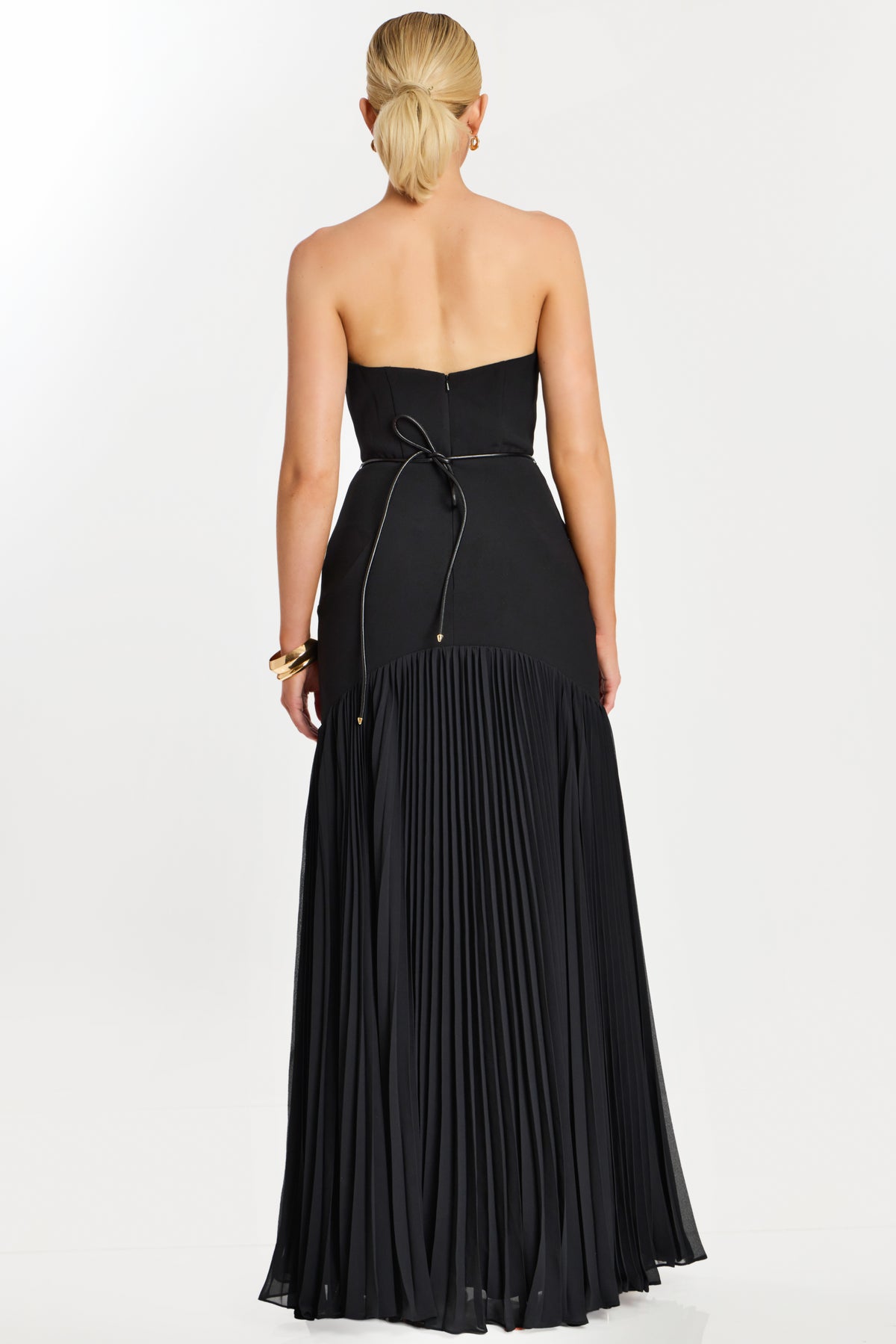 Model wearing Jovani 47000 strapless evening gown with floral waist detail and flowing pleated skirt.