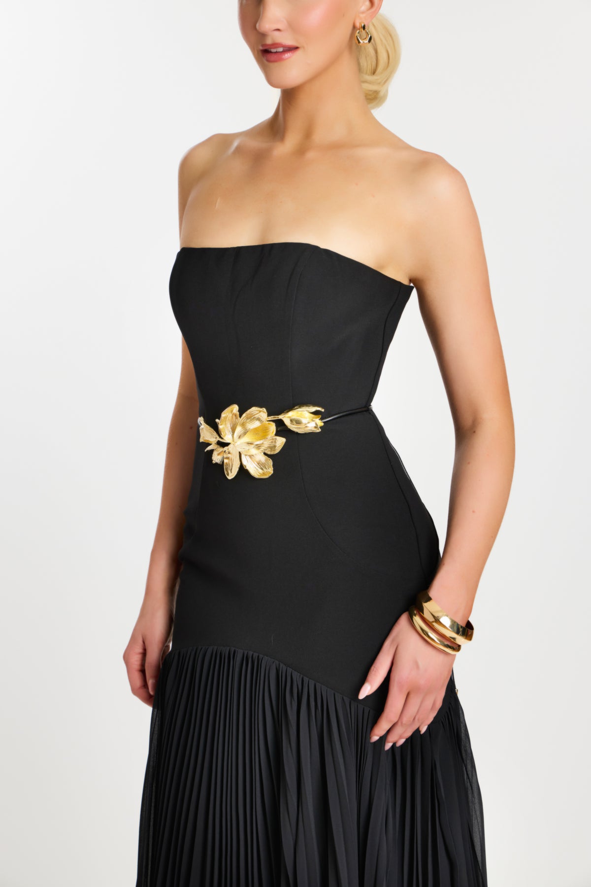 Model wearing Jovani 47000 strapless evening gown with floral waist detail and flowing pleated skirt.