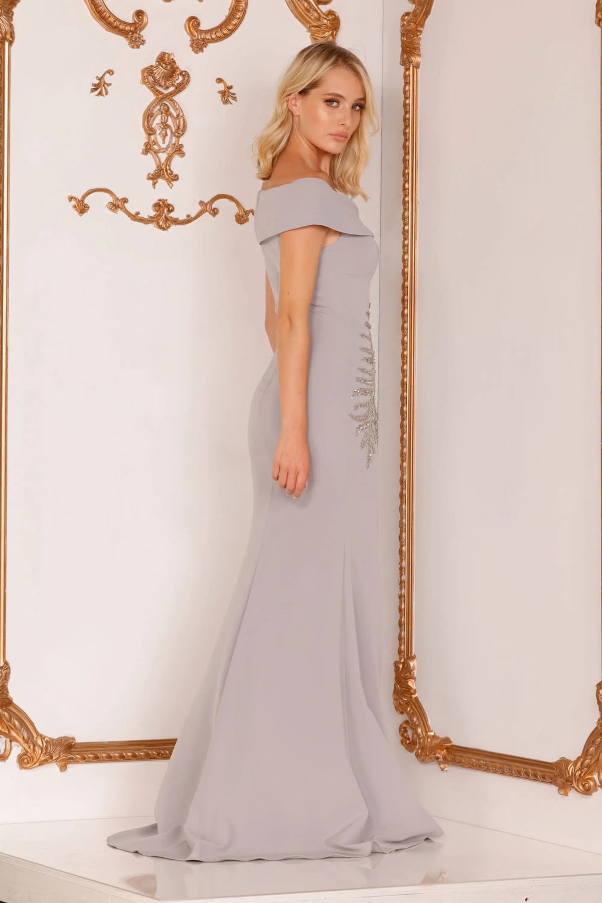 Make a statement in this stunning Terani Couture off-shoulder mother of the bride dress. The trumpet cut, asymmetrical crystal embellishments, and side slit create a glamorous silhouette. Perfect for any formal occasion. Sold by Madeline's Boutique in Toronto, Canada and Boca Raton, Florida