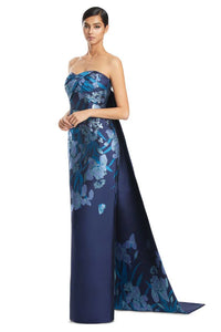 Model wearing Alexander by Daymor 3262S26 strapless floral column gown with draped bodice and statement back detail.