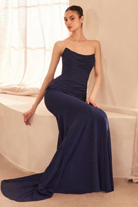 Woman wearing a long navy blue one-shoulder dress sitting on a couch.