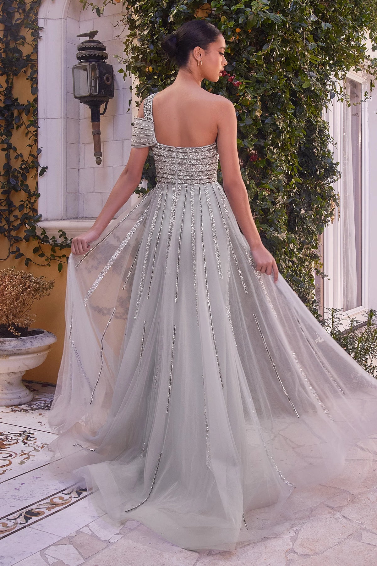 Andrea&Leo A1314 Allure Silver Evening Gown - A fitted silver gown adorned with fully linear beading, featuring intricately beaded cold shoulder detail, a leg slit, and an embellished tulle back overskirt for a contemporary and sophisticated look.