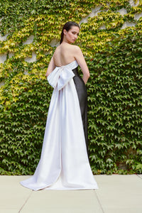 Model wearing Audrey+Brooks 6420 strapless black and white gown featuring a back bow and train.