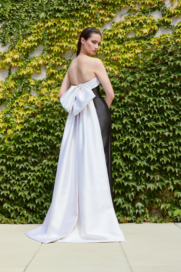 Model wearing Audrey+Brooks 6420 strapless black and white gown featuring a back bow and train.