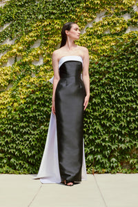 Model wearing Audrey+Brooks 6420 strapless black and white gown featuring a back bow and train.