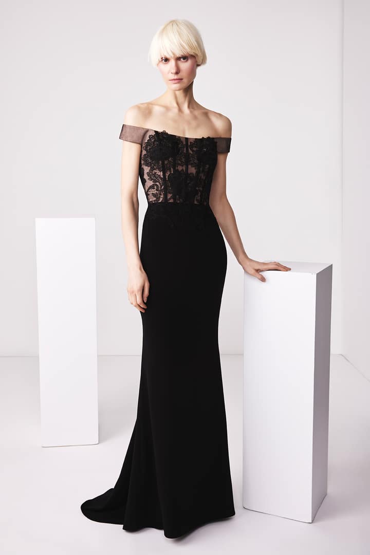 Model wearing Audrey+Brooks 6503 off-the-shoulder gown with sheer lace bodice and fit and flare silhouette.