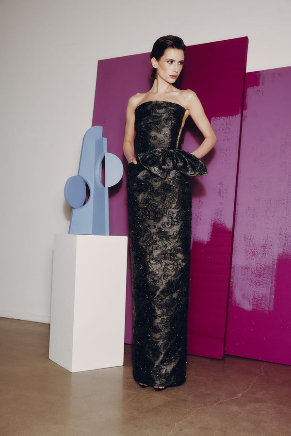 Model wearing Audrey+Brooks 6904 strapless evening gown with bow detail and column silhouette.