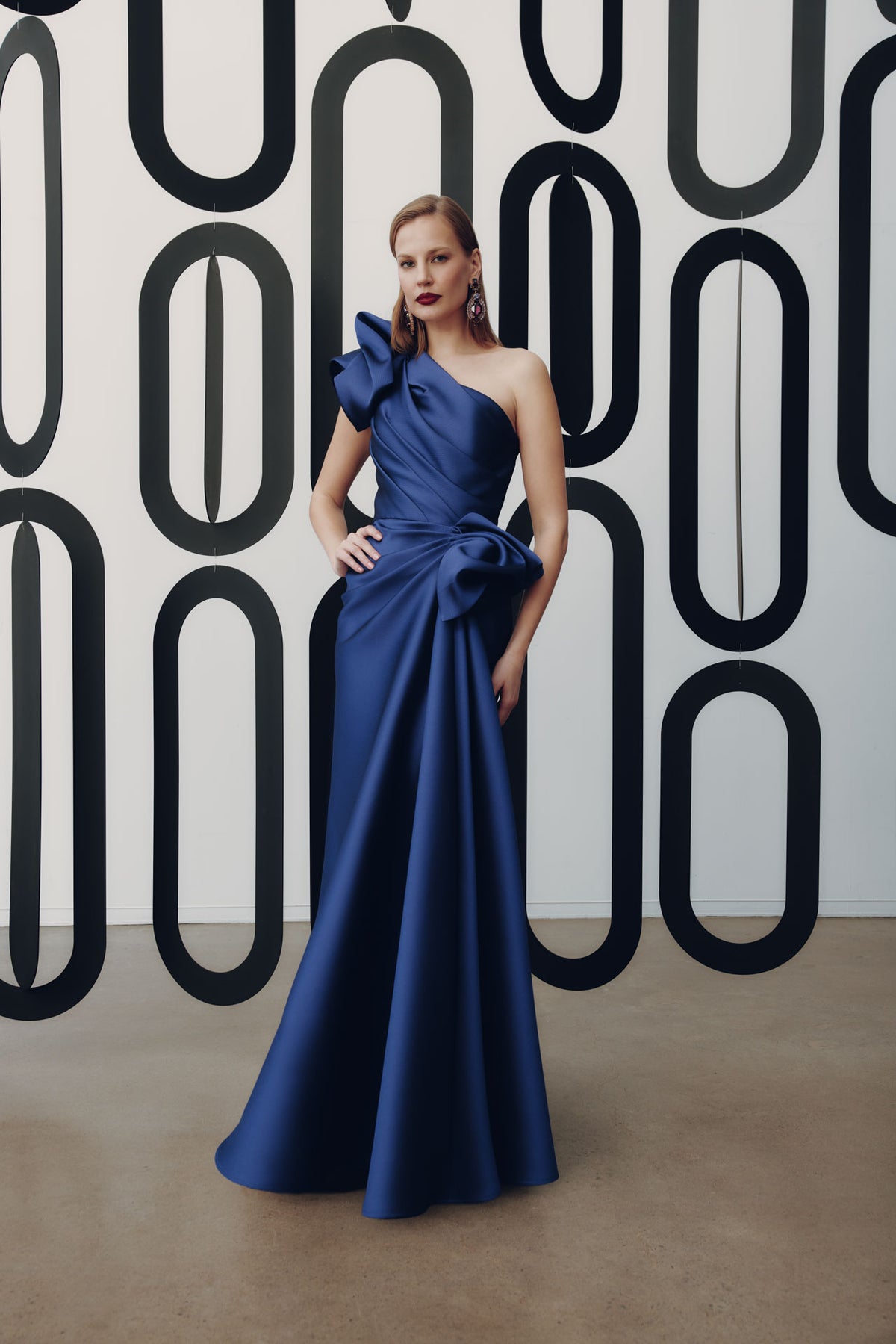 Model wearing Frascara 4927 one-shoulder gown with draped bodice, asymmetrical peplum, and fit-and-flare skirt.  Model is wearing the color amethyst.  Front View.