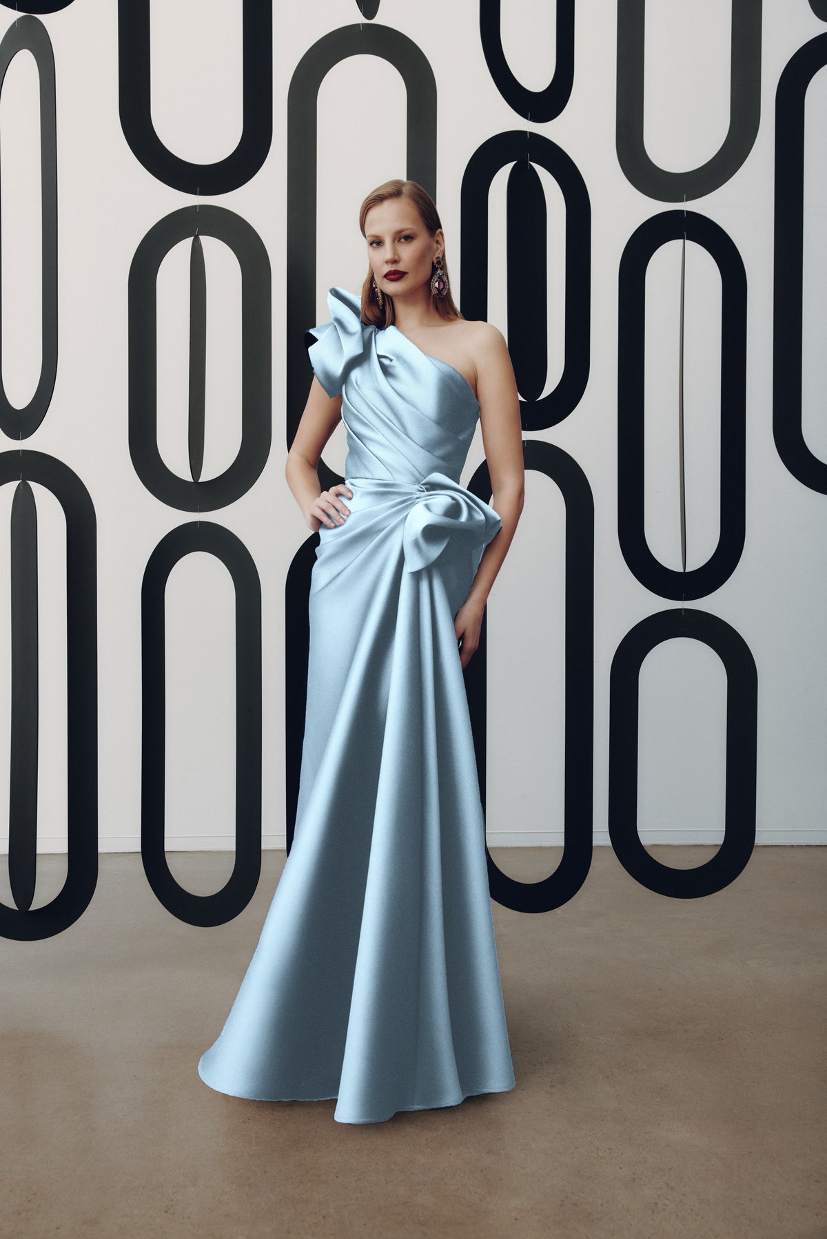 Model wearing Frascara 4927 one-shoulder gown with draped bodice, asymmetrical peplum, and fit-and-flare skirt.  Model is wearing the color azure.  Front View.