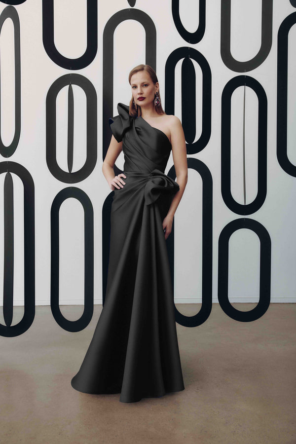 Model wearing Frascara 4927 one-shoulder gown with draped bodice, asymmetrical peplum, and fit-and-flare skirt.  Model is wearing the color black.  Front View.