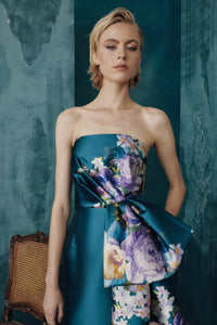 Woman wearing a strapless dress with floral design against a textured teal background