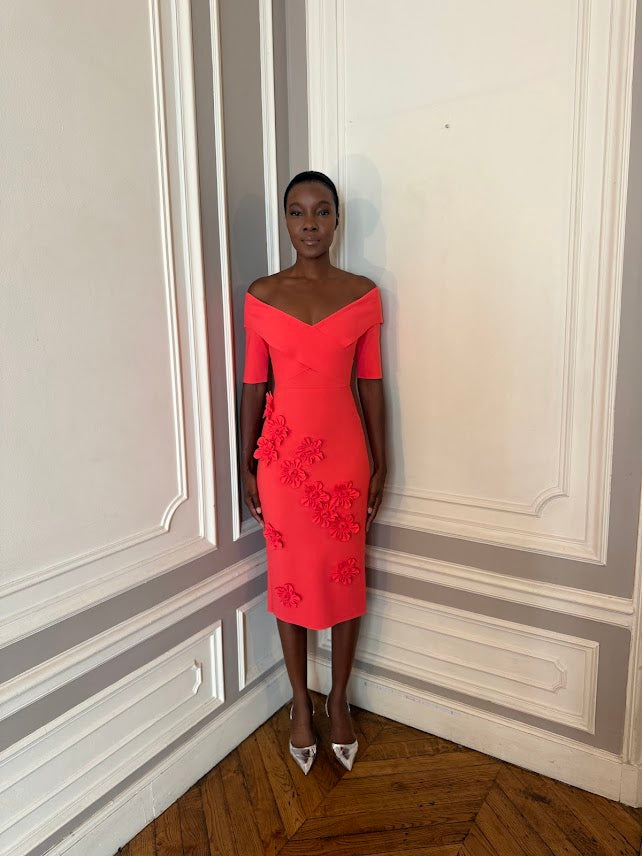 Woman in a red dress standing in a room with decorative wall paneling.
