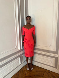 Woman in a red dress standing in a room with decorative wall paneling.