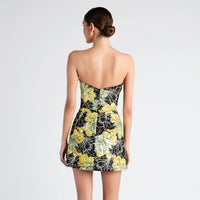 Woman wearing a strapless floral dress on a plain background