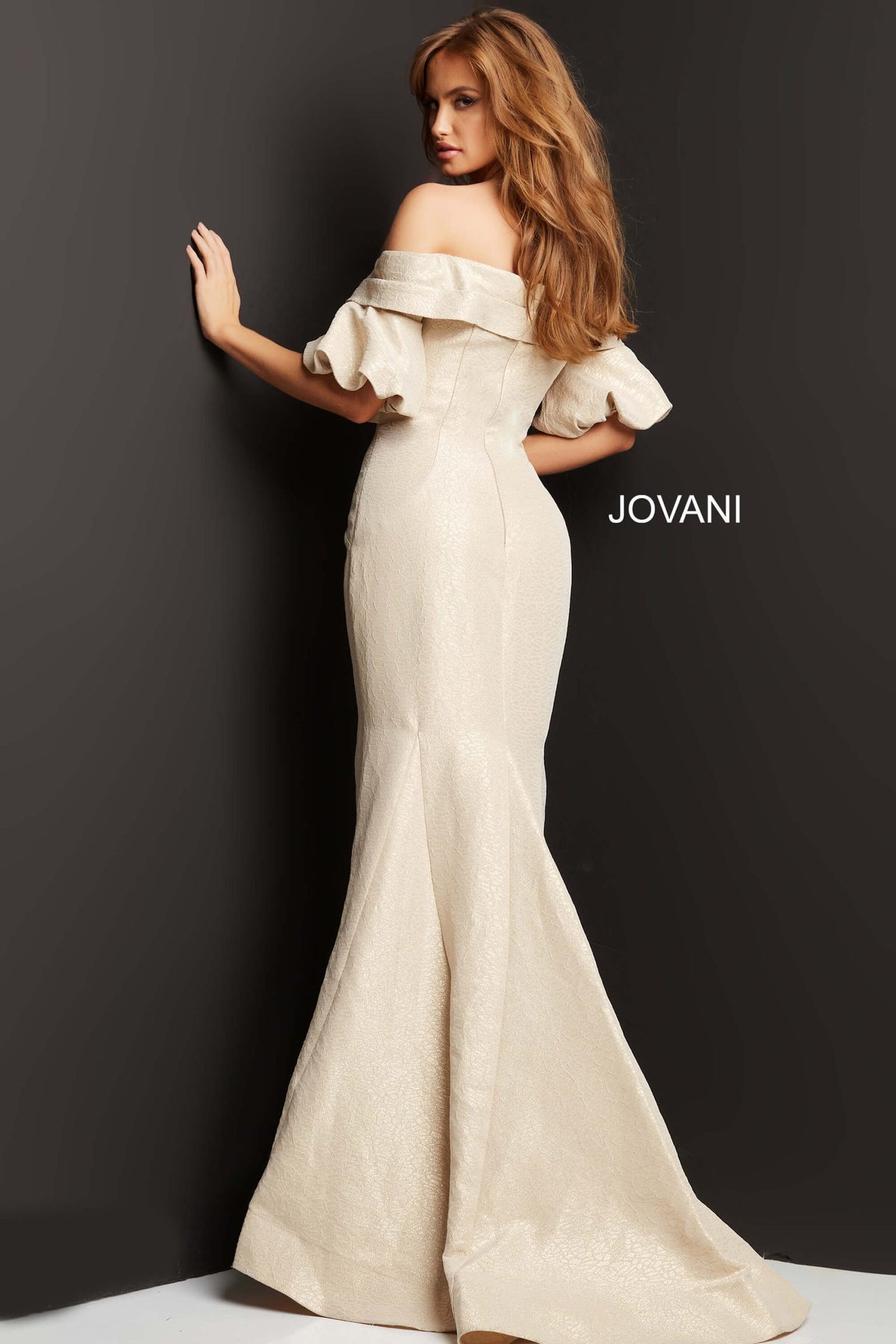 Model wearing Jovani 06831 off-the-shoulder puff sleeve mermaid gown with crossover bodice.