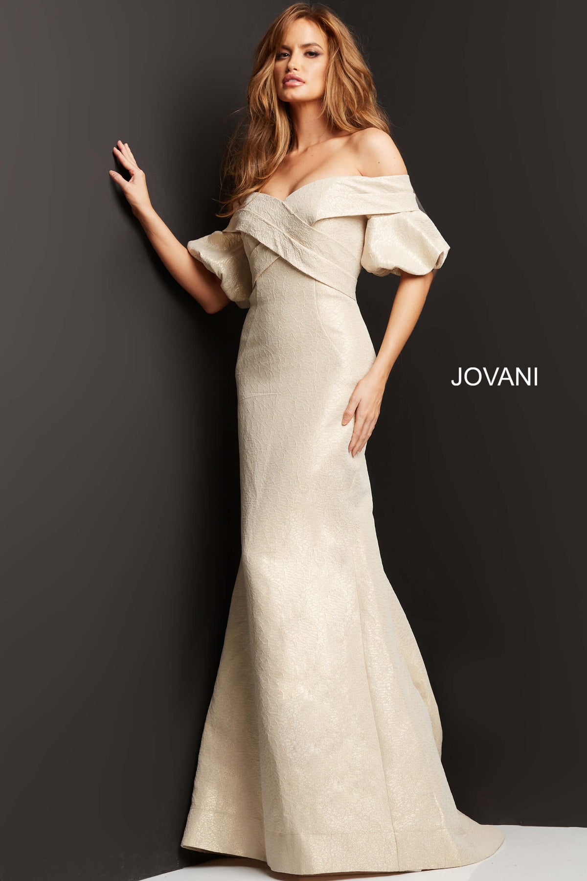 Model wearing Jovani 06831 off-the-shoulder puff sleeve mermaid gown with crossover bodice.