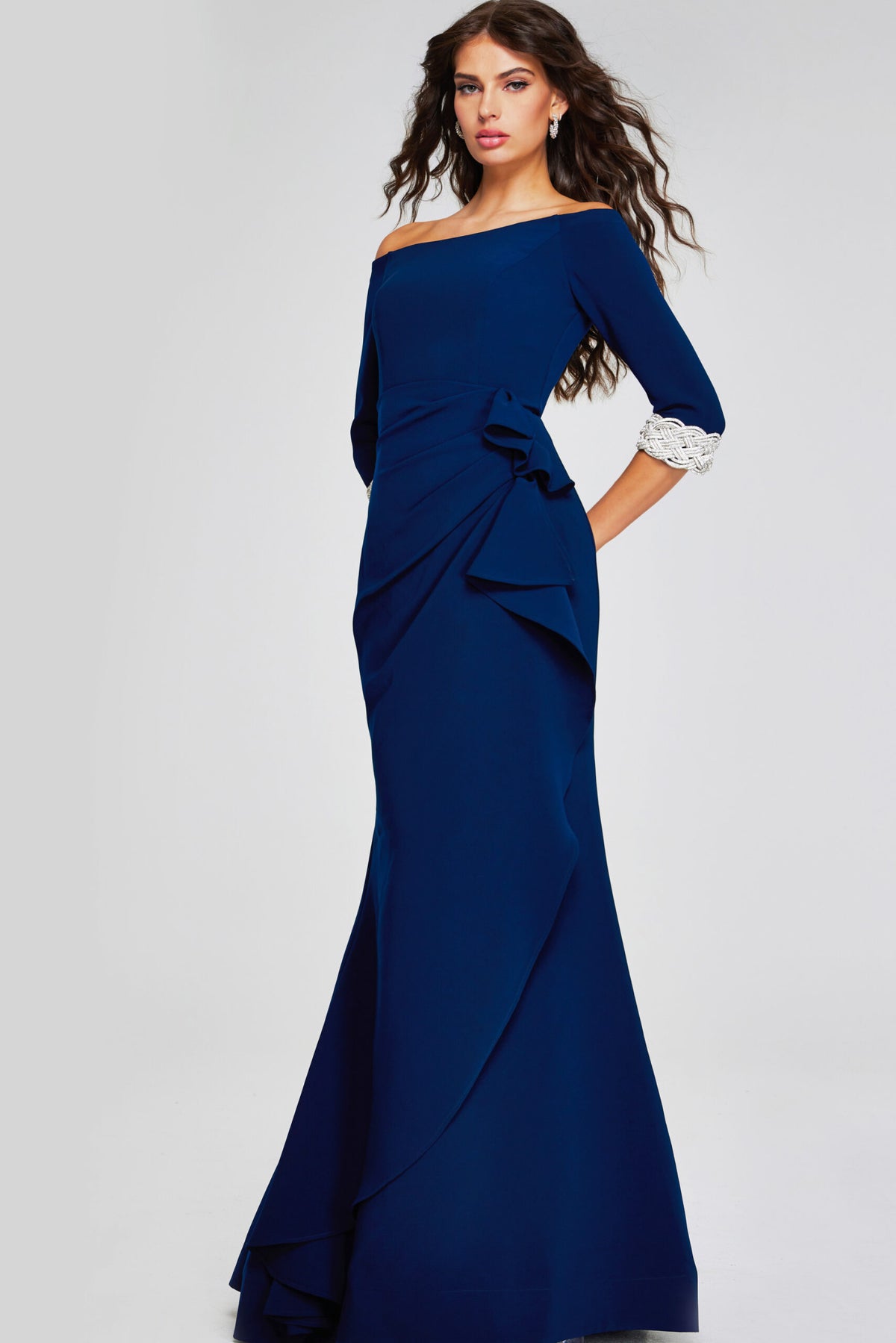 Model wearing Jovani 42409 off-the-shoulder gown with three-quarter sleeves, embellished cuffs, and draped side detail.