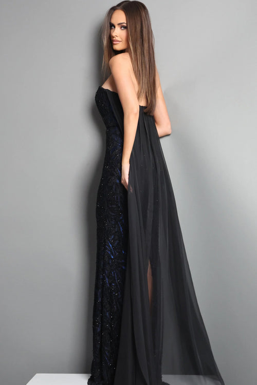 Woman wearing a black evening gown with a sheer overlay against a gray background