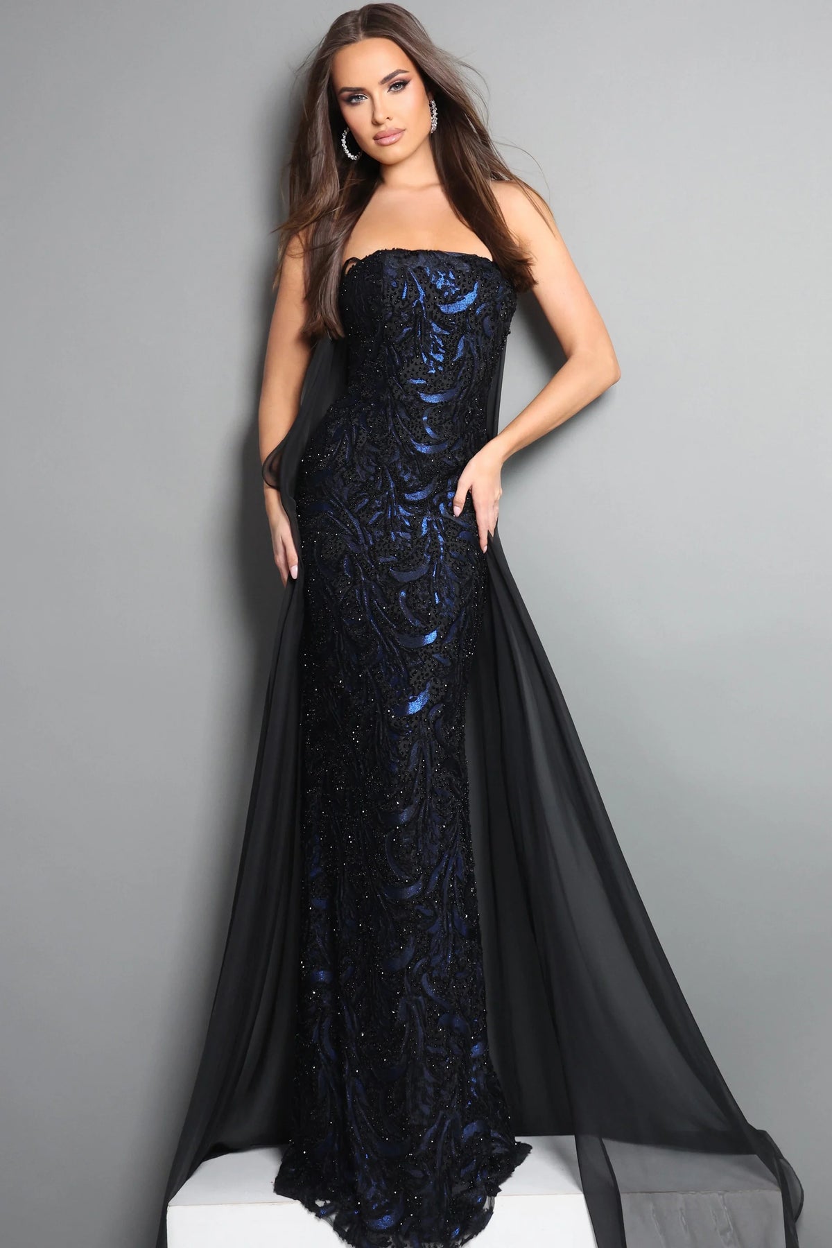 Woman wearing a black and blue evening gown against a gray background