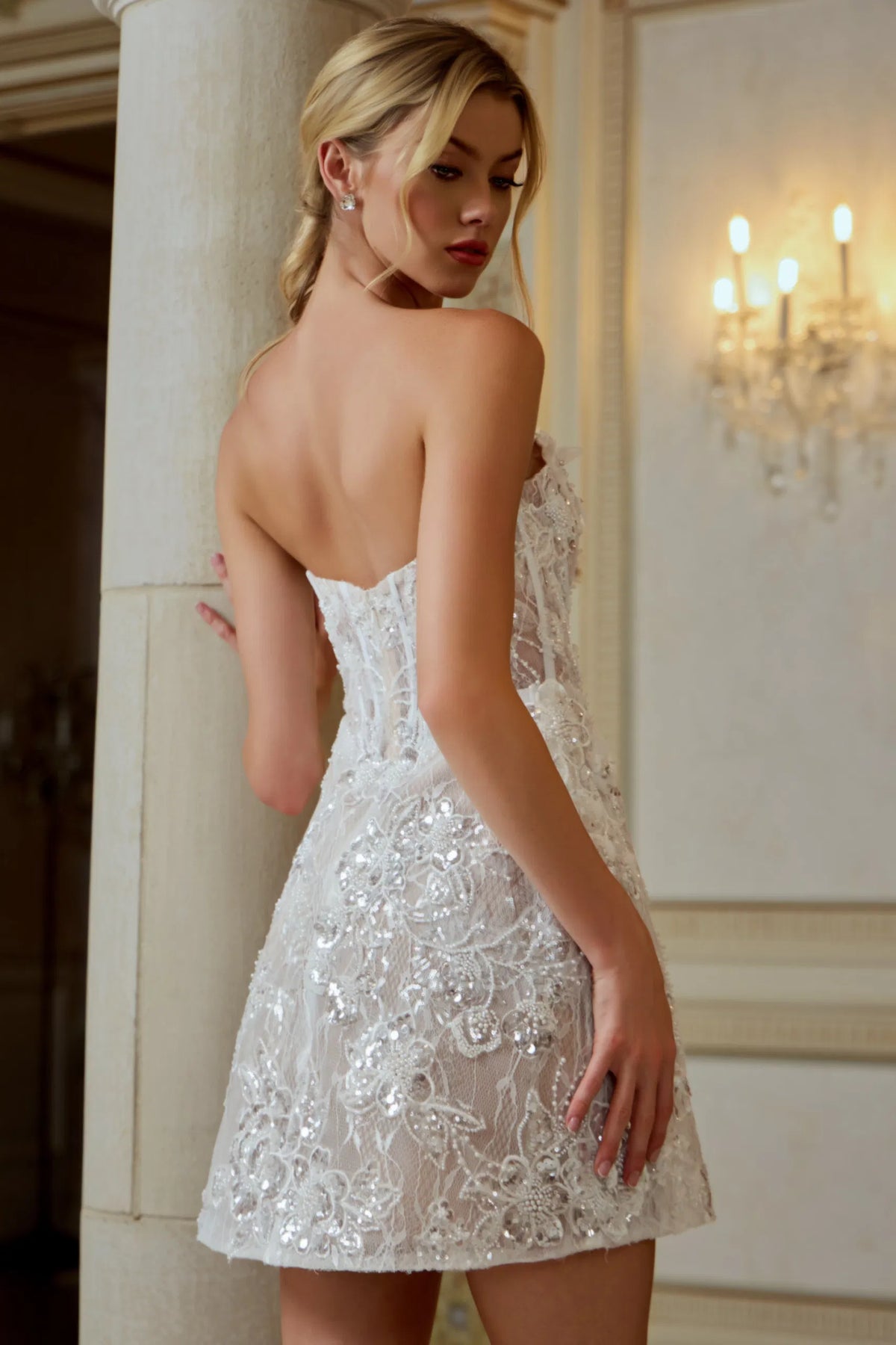 Woman wearing a white lace wedding dress in an elegant indoor setting.