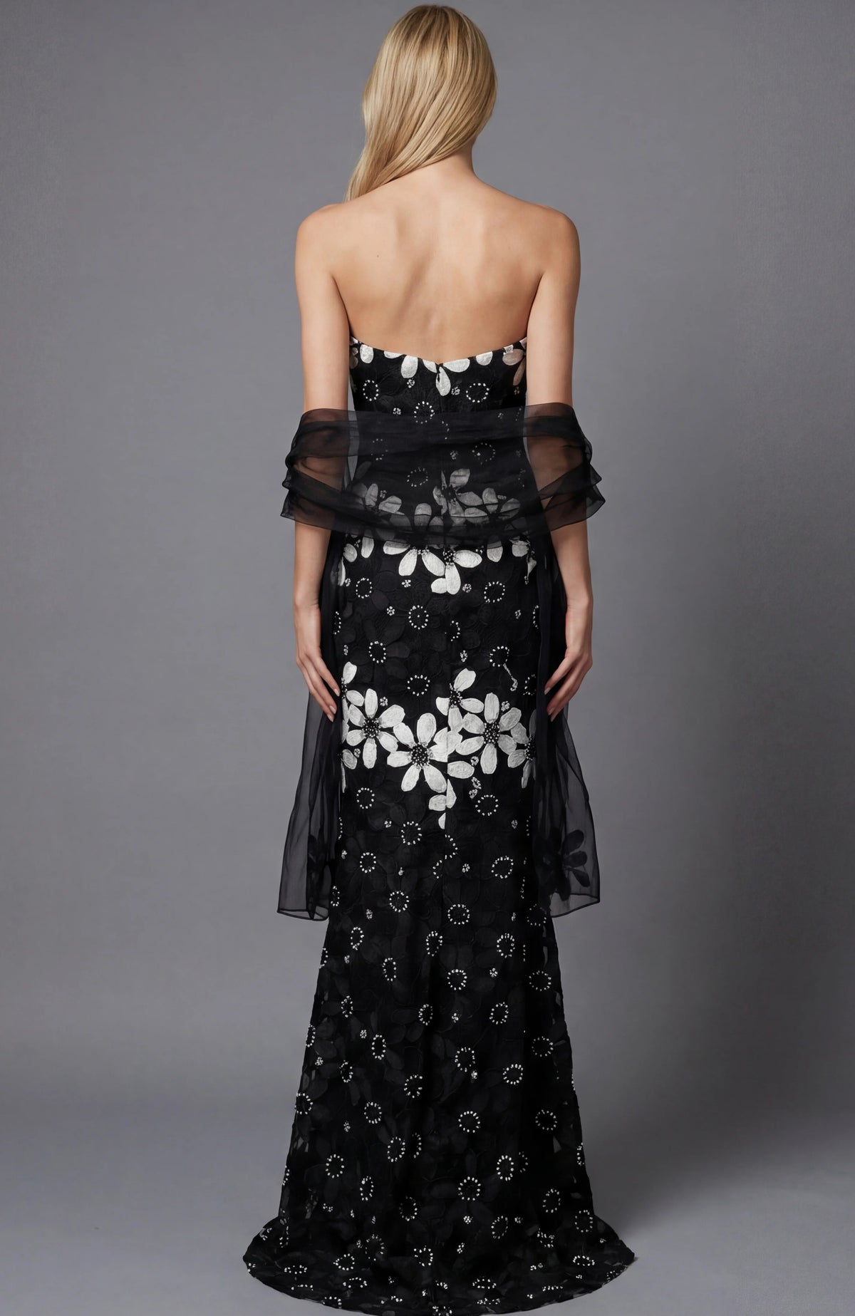 Black strapless evening gown with white floral pattern on a gray background