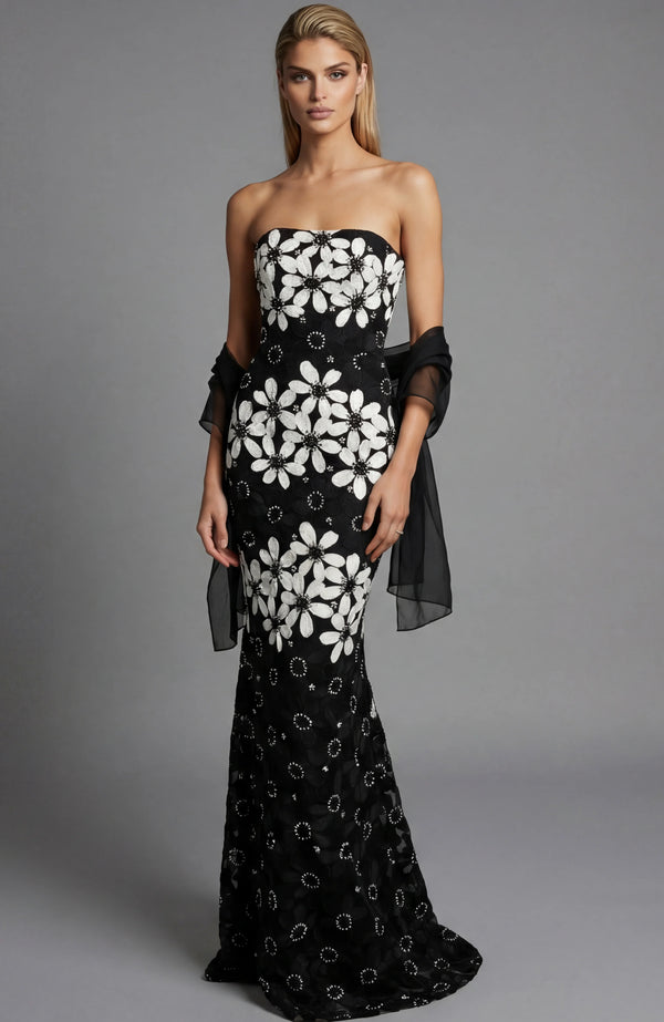 Woman wearing a black strapless gown with white floral patterns on a gray background