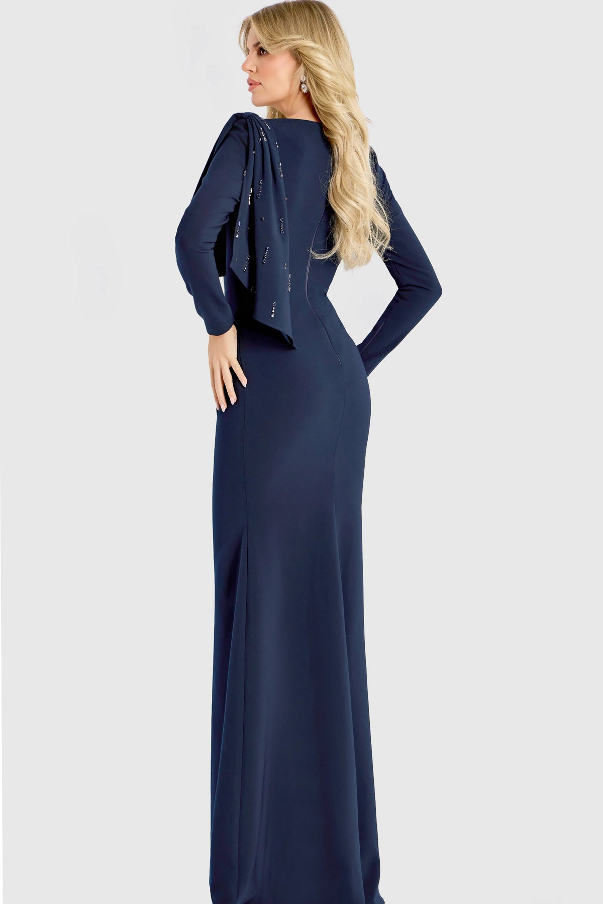 Model wearing Jovani 46738 evening gown featuring a bateau neckline, beaded shoulder detail, long sleeves, and an elegant cape drape.