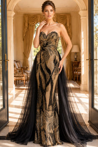 Woman in a black and gold evening gown standing in a luxurious room with large windows.