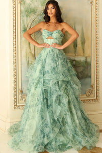 Woman wearing a green strapless gown in front of an ornate mirror.