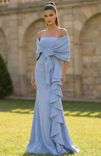 Woman wearing a light blue off-shoulder gown with ruffled layers in an outdoor setting.
