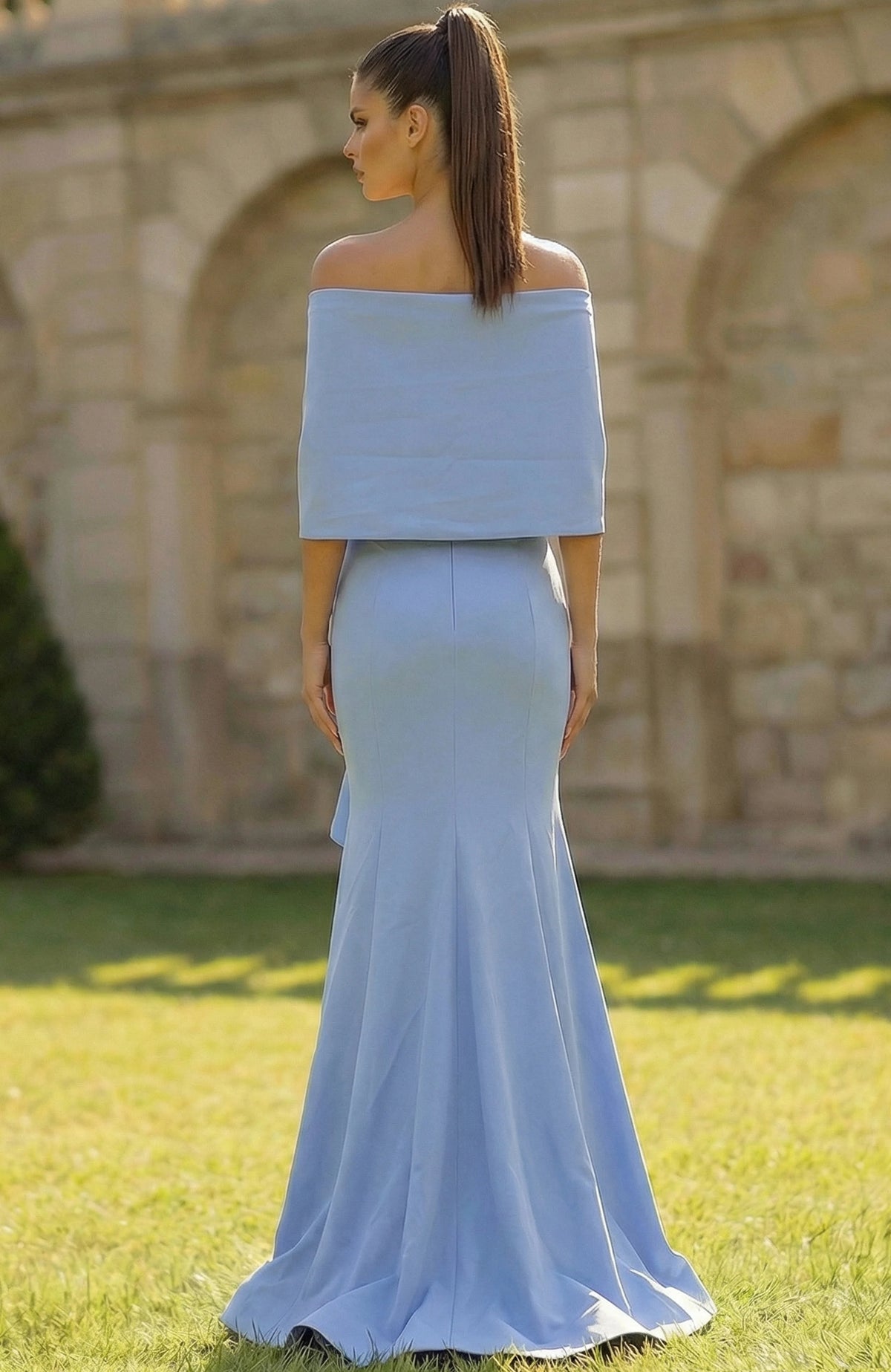 Woman wearing a light blue off-shoulder top and mermaid-style skirt in an outdoor setting.