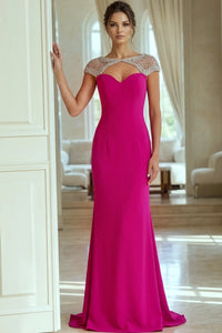 Woman wearing a fuchsia evening gown with a beaded neckline in an elegant room.