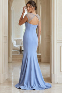 A woman modeling a light blue mermaid-style evening gown from the back, standing in a grand interior hallway with cream-colored columns and arches.