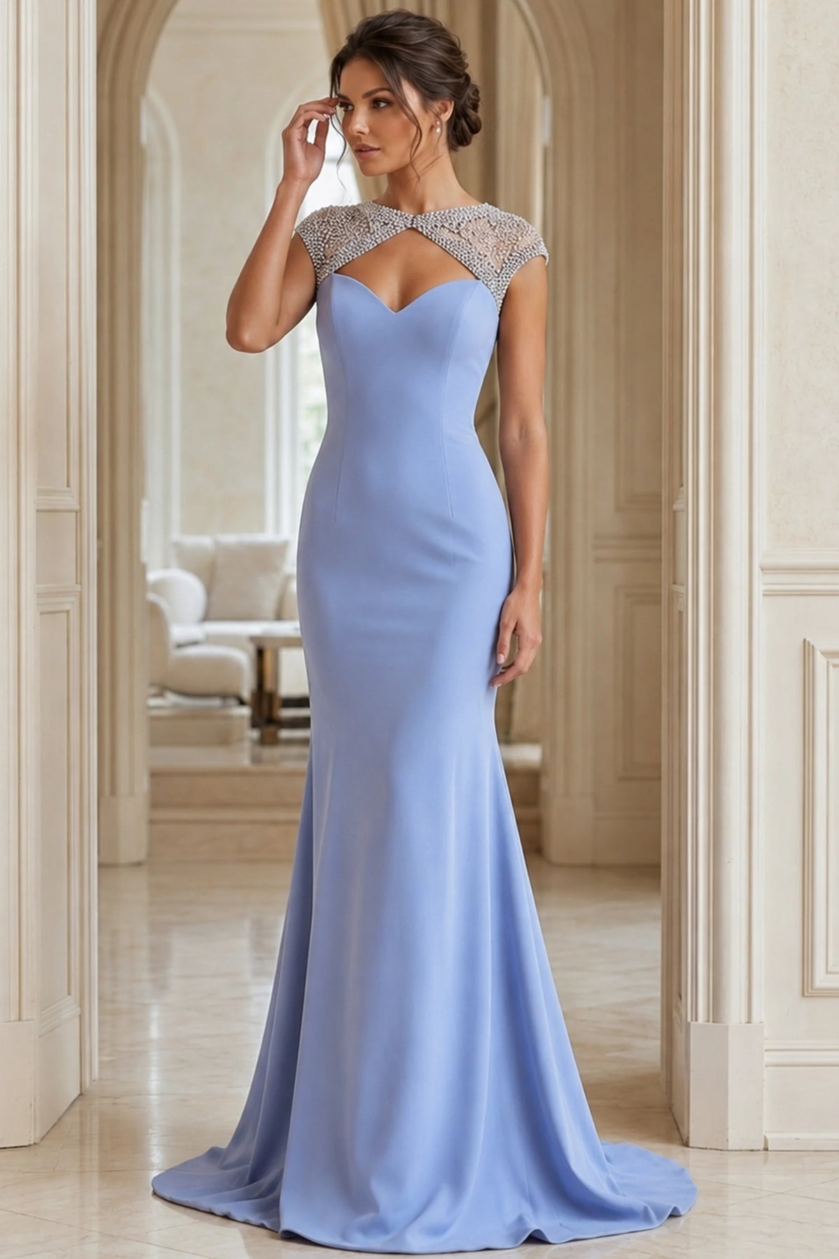 Woman wearing a light blue evening gown with a beaded neckline in an elegant interior setting.