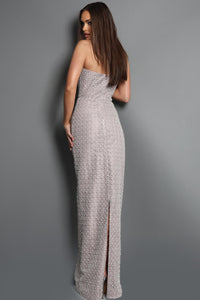 Woman wearing a silver strapless gown with a slit on a gray background