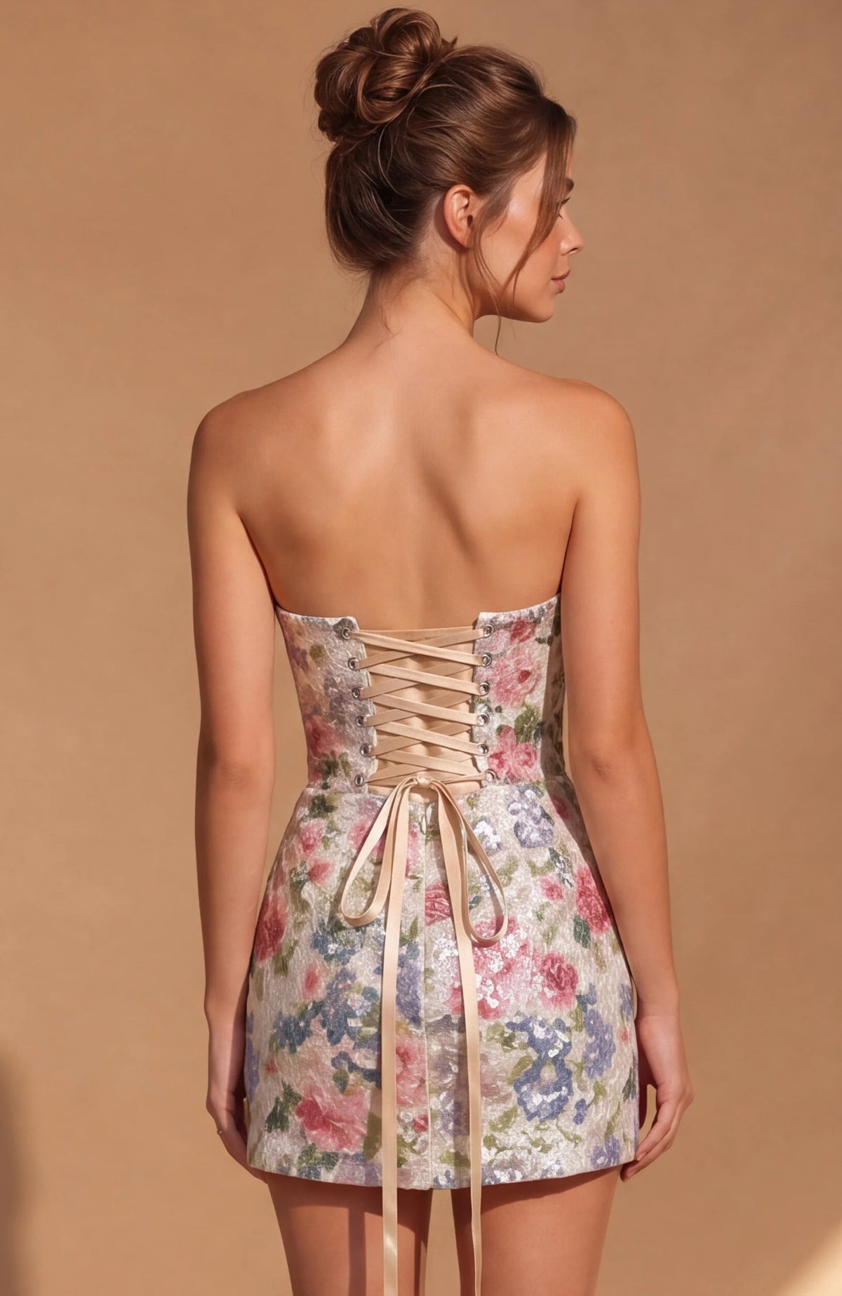 Woman wearing a strapless floral dress with a beige lace-up back on a brown background