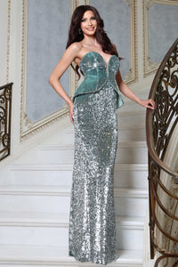 A woman models a strapless floor-length evening gown with a mint green peplum bodice and silver sequined skirt, posing on an elegant white staircase with a gold-toned railing.