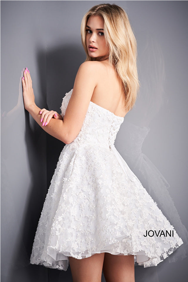 A strapless fit and flare dress with floral appliques, ideal for Bat Mitzvahs, graduations, and homecoming events. Model is wearing the dress in white.