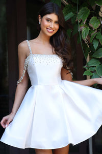 Woman wearing a white dress with beaded straps against a natural background