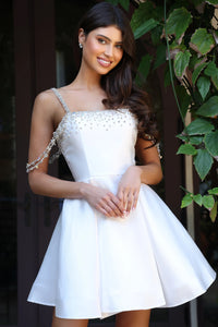 Woman wearing a white dress with embellishments in an outdoor setting
