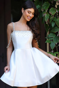 Woman wearing a white dress with decorative straps in an outdoor setting