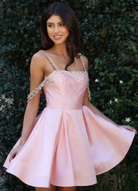 Woman wearing a pink dress with beaded straps against a green leafy background