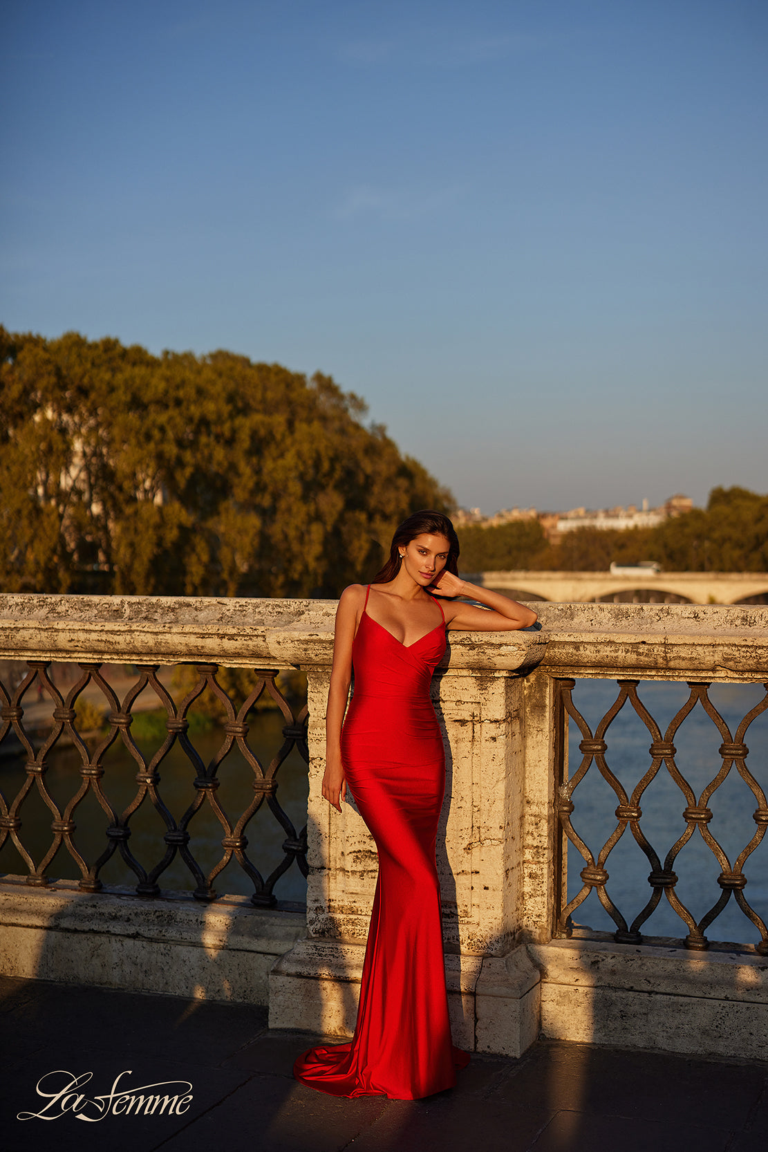 La Femme 31618 Chic Fitted Long Jersey Prom Dress - A sophisticated prom dress with a chic fitted silhouette, ruching detail, criss-cross style bodice, and an open back with a lace-up tie. Model is wearing the dress in the color red.