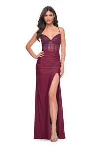 La Femme 31988 Rhinestone Embellished Lace Bodice Prom Gown - A glamorous long dress featuring a ruched jersey skirt, high slit, rhinestone embellished lace bodice with exposed boning, lace-up back, and ruching along the zipper for a perfect fit. The model is wearing the dress in dark Berry. Front view