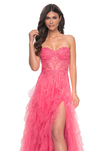 La Femme 32286 Illusion Lace Bustier A-Line Prom Gown - A captivating A-line gown featuring a ruffle tulle skirt, high slit, and illusion lace bustier bodice for a glamorous and sophisticated prom look. The model is wearing the dress in the color coral.