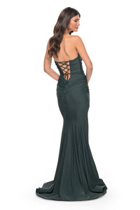 La Femme 32289 Soft Jersey Mermaid Prom Dress - A captivating prom dress in soft jersey with a flattering mermaid silhouette, draped neckline, lace-up back, and a structured hem. The model is wearing the dress in the color dark emerald.