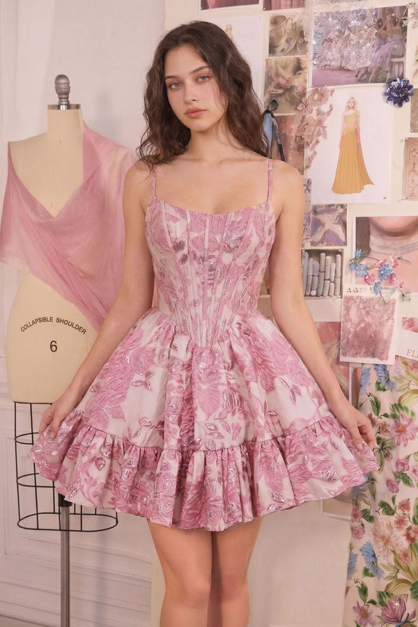 Woman wearing a pink floral dress in a room with mannequin and fabric.