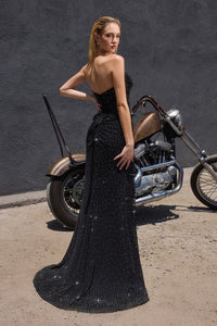 Model wearing Ladivine CD388 gown featuring a draped strapless neckline, sheer corset bodice, and high leg slit.  The model is wearing the dress in black.  Back View.