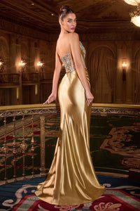 Woman in a gold evening gown standing in an opulent room with chandeliers.