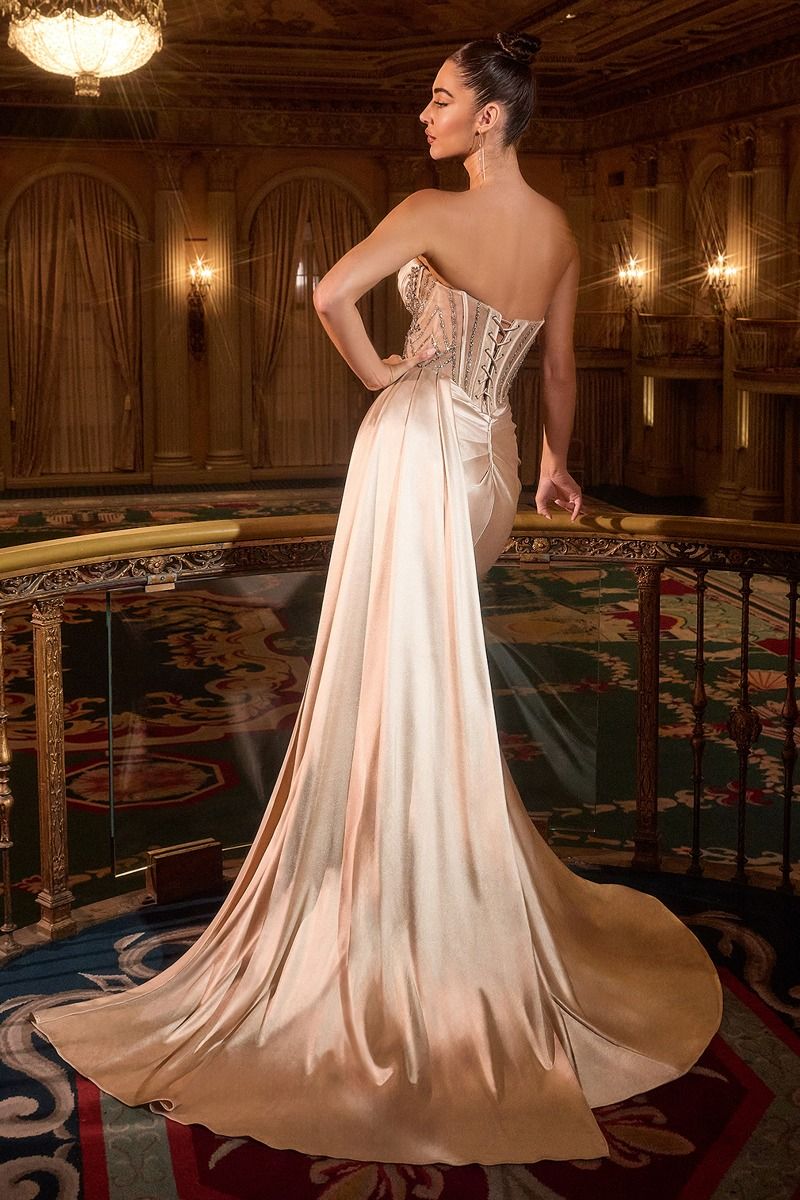 Model wearing Ladivine KV1131 strapless sweetheart gown with embellished bodice, leg slit, and flowing satin sash.